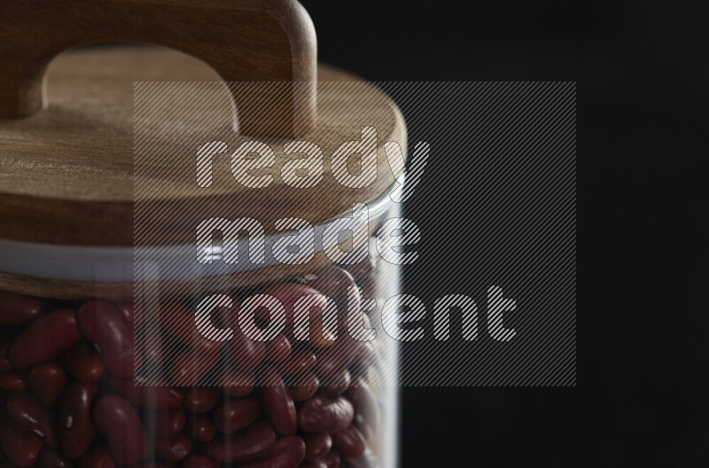 Red kidney beans in a glass jar on black background