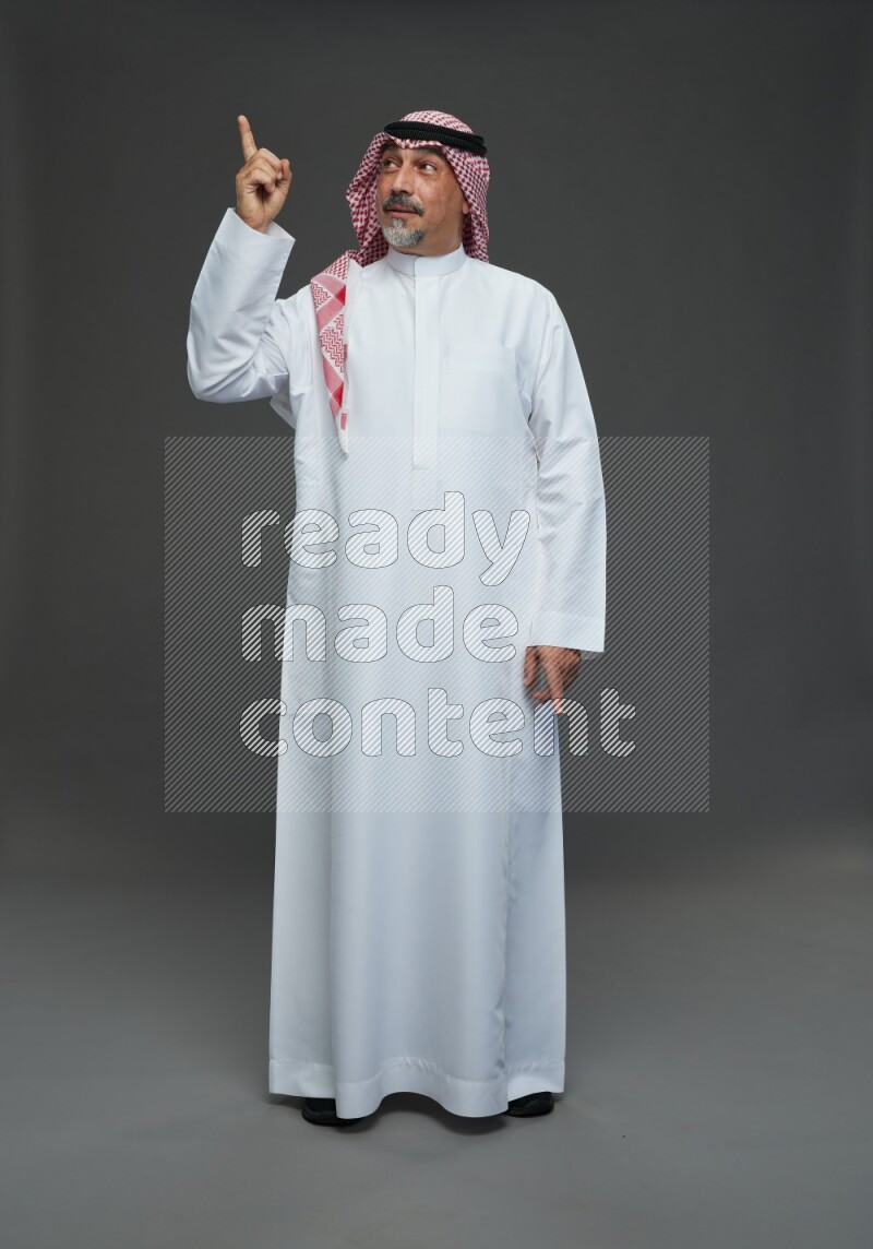 Saudi man with shomag Standing Interacting with the camera on gray background
