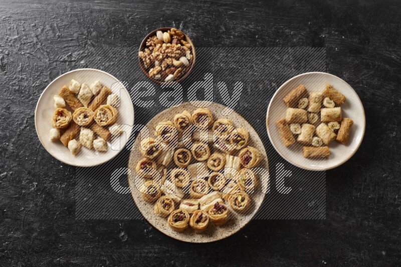 Oriental sweets in pottery plates with nuts in a dark setup
