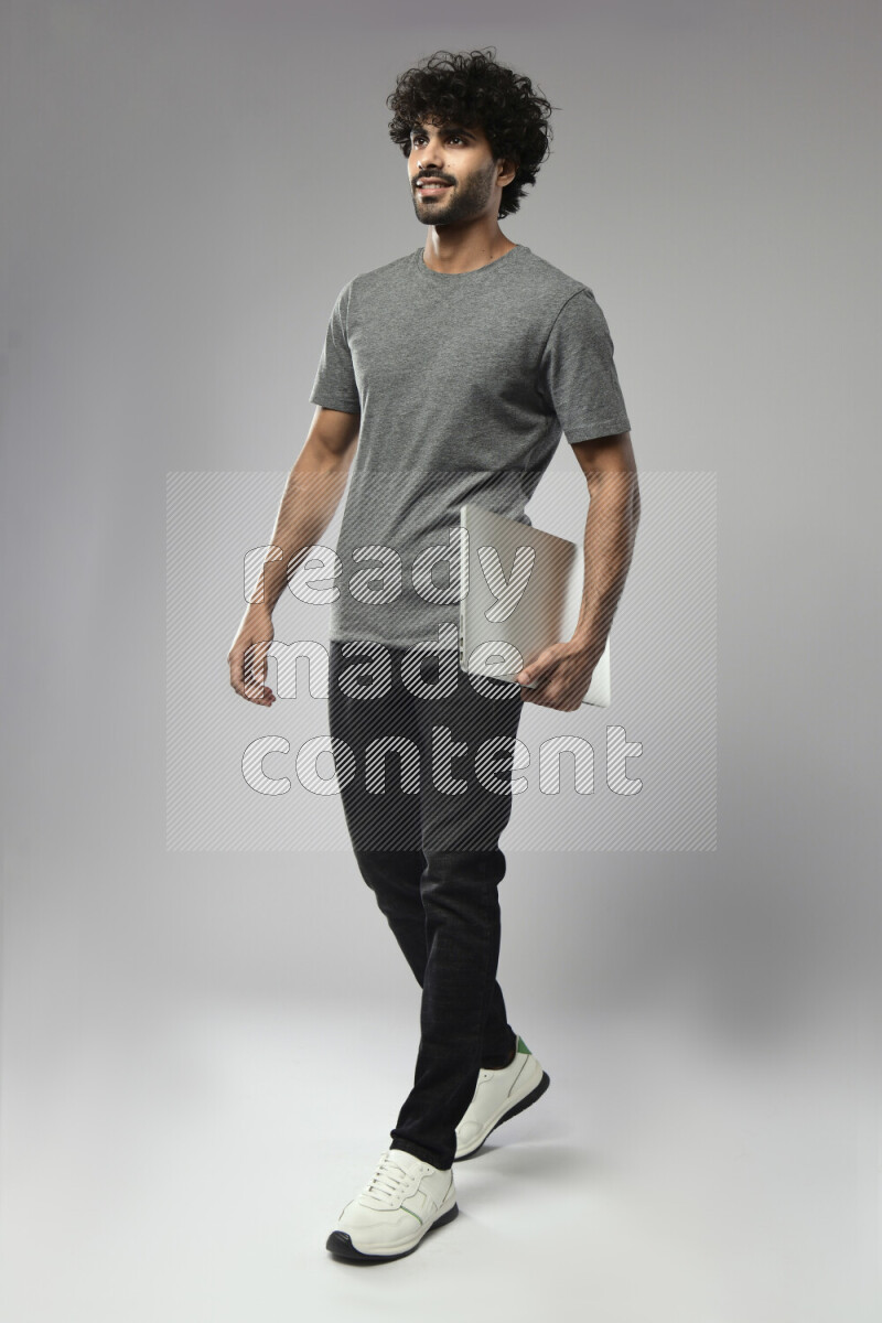 A man wearing casual standing and holding a laptop on white background