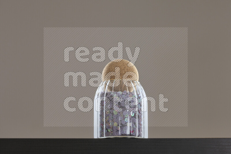 Sequins in a glass jar on black background