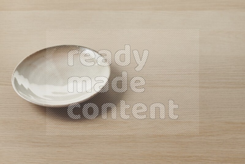 A beige pottery plate on light wooden background