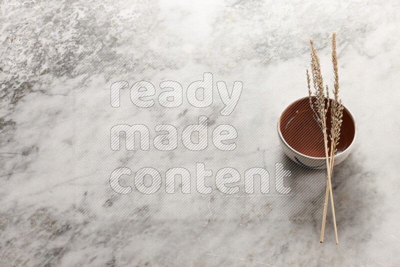 Wheat stalks on brown pottery bowl on grey marble background