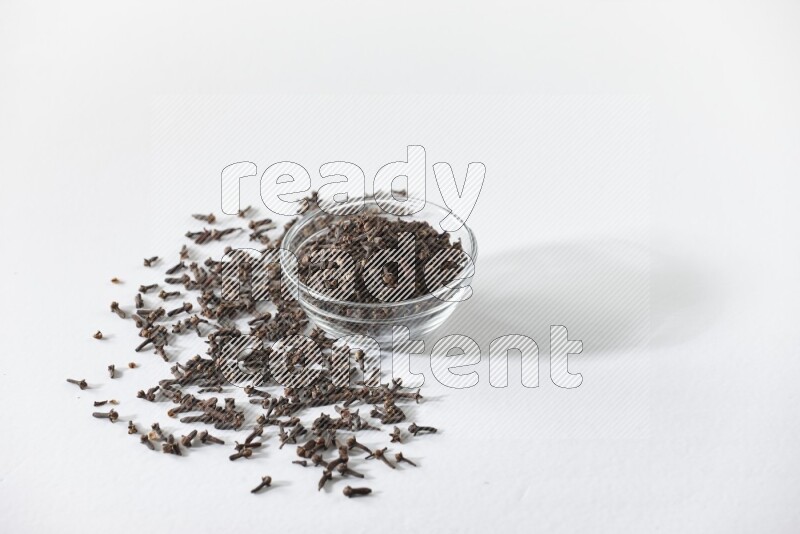 A glass bowl full of cloves on a white flooring