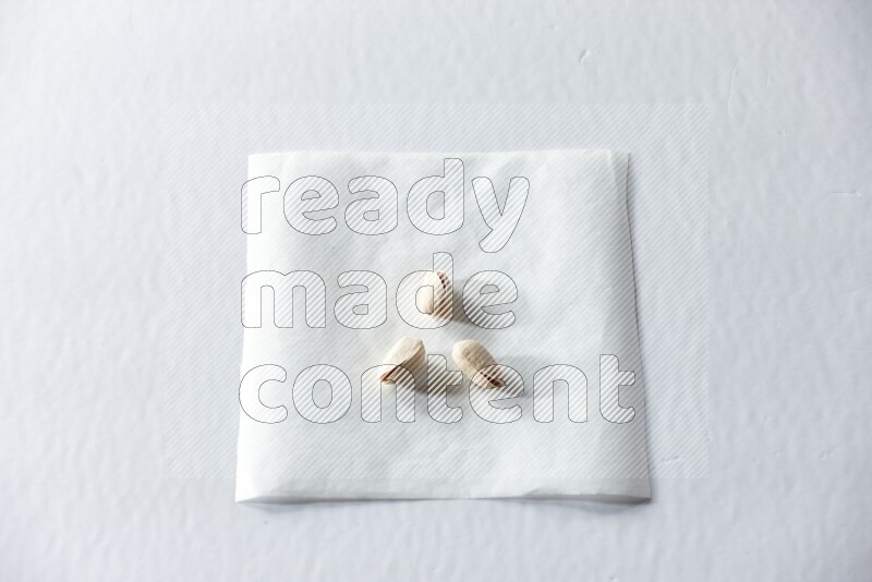 3 pistachios on a piece of paper on a white background in different angles