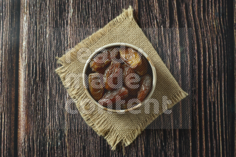 Dates in different bowls (wooden, pottery and glass) on wooden background
