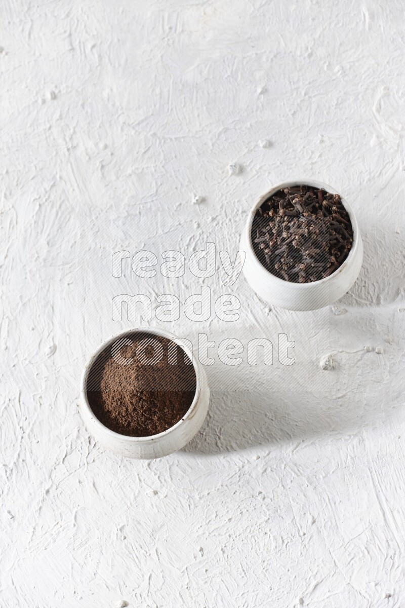 وعاءين من السيراميك بيج اللون، أحدهما مملوء بالقرنفل والآخر مملوء بالبودرة على أرضية بيضاء