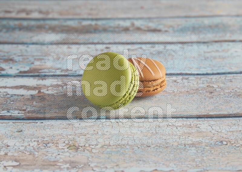 45º Shot of of two assorted Brown Irish Cream, and Green Pistachio macarons  on light blue background