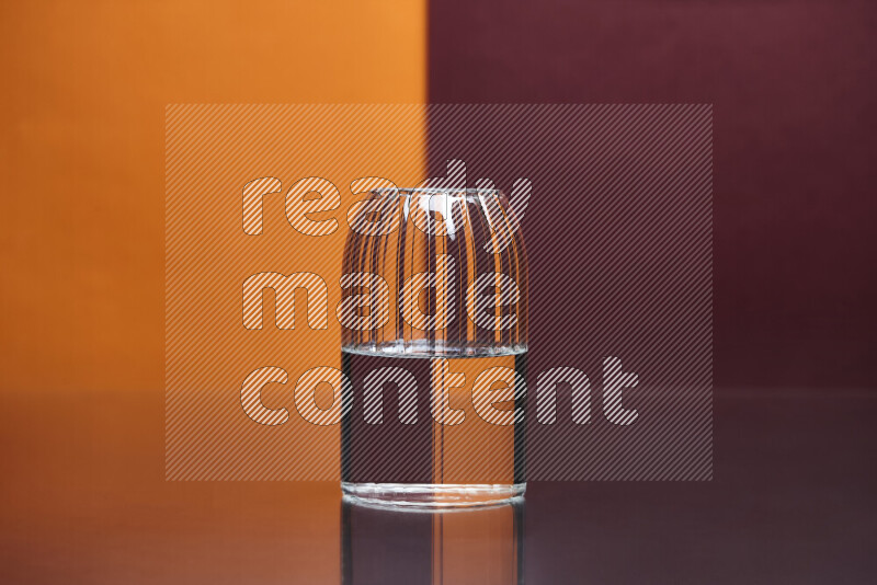 The image features a clear glassware filled with water, set against orange and dark red background
