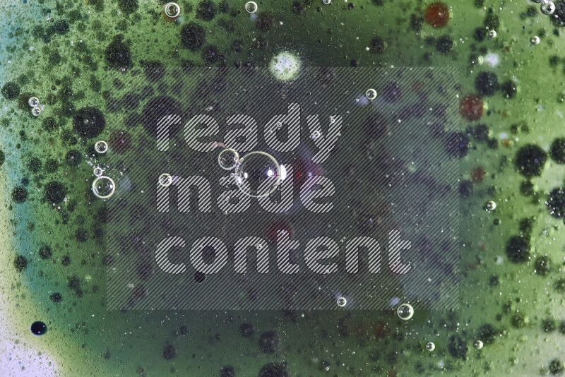 لقطات مقربة لقطرات ألوان مائية حمراء وخضراء وزرقاء على سطح الزيت على خلفية خضراء