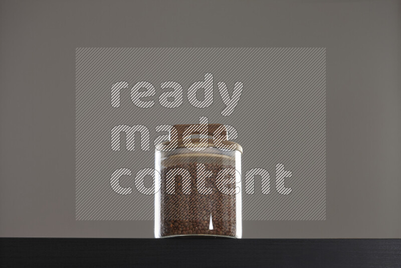 Brown lentils in a glass jar on black background