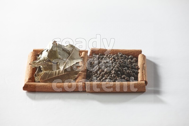 2 squares of cinnamon sticks full of black peppers and bay laurel leaves on white flooring