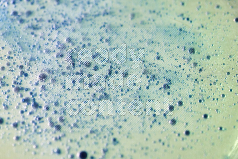 Close-ups of abstract blue watercolor drops on oil Surface on green background