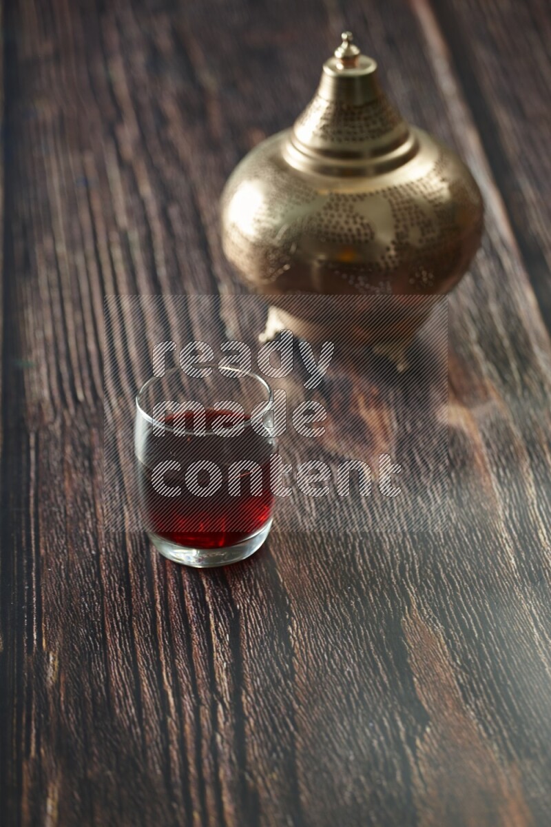A golden lantern with different drinks, dates, nuts, prayer beads and quran on brown wooden background