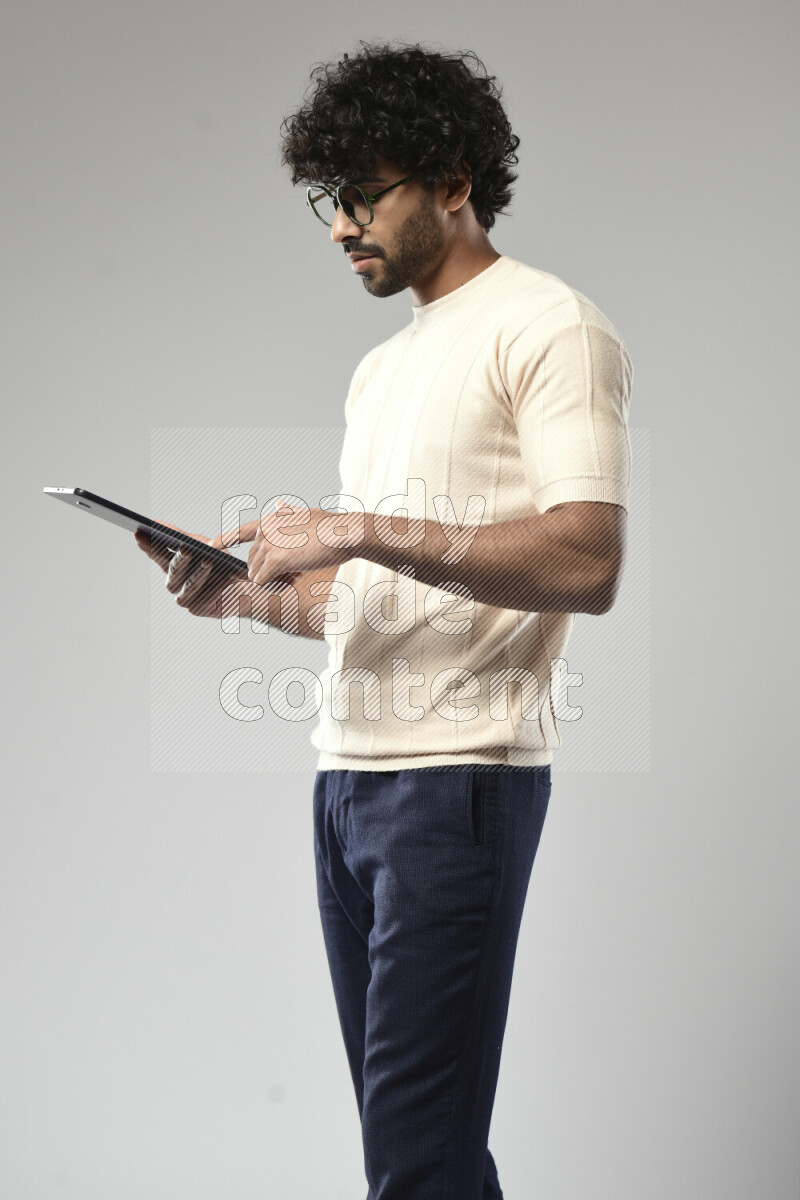 A man wearing casual standing and browsing on a tablet on white background