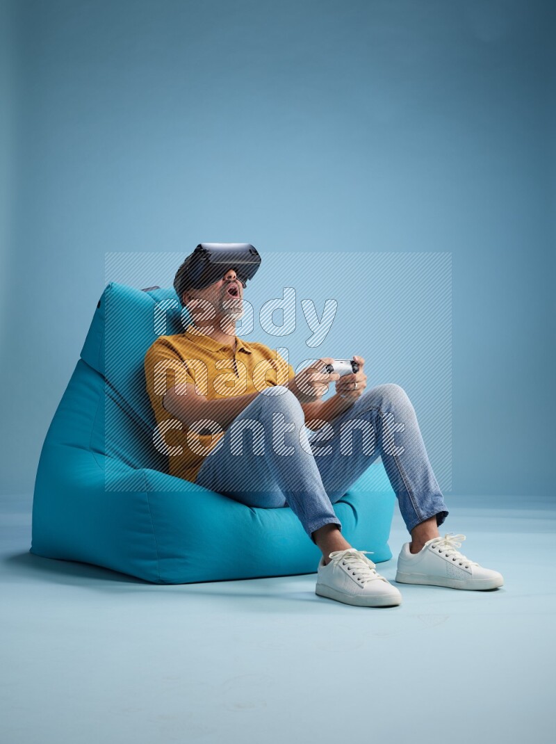 A man sitting on a blue beanbag and gaming with VR