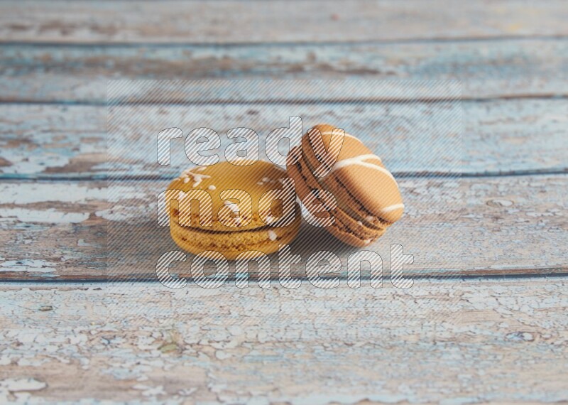 45º Shot of of two assorted Brown Irish Cream, and Yellow Piña Colada macarons on light blue background
