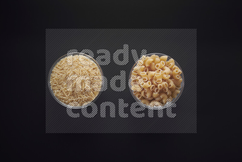 Different pasta types in glass bowls on black background