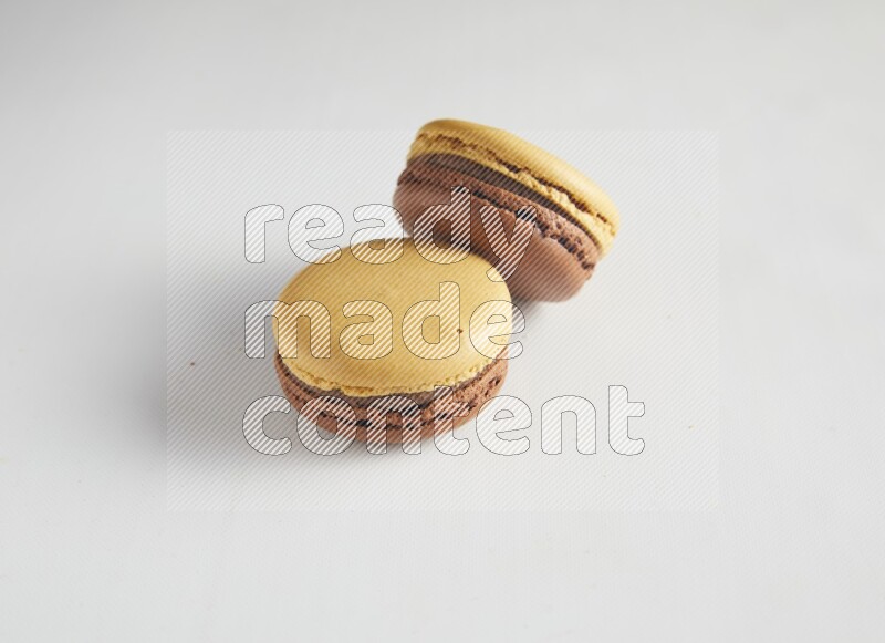 45º Shot of two Yellow and Brown Chai Latte macarons on white background