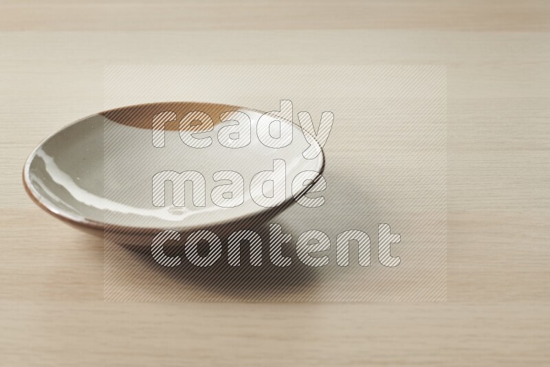 A multicolored pottery plate on light wooden background