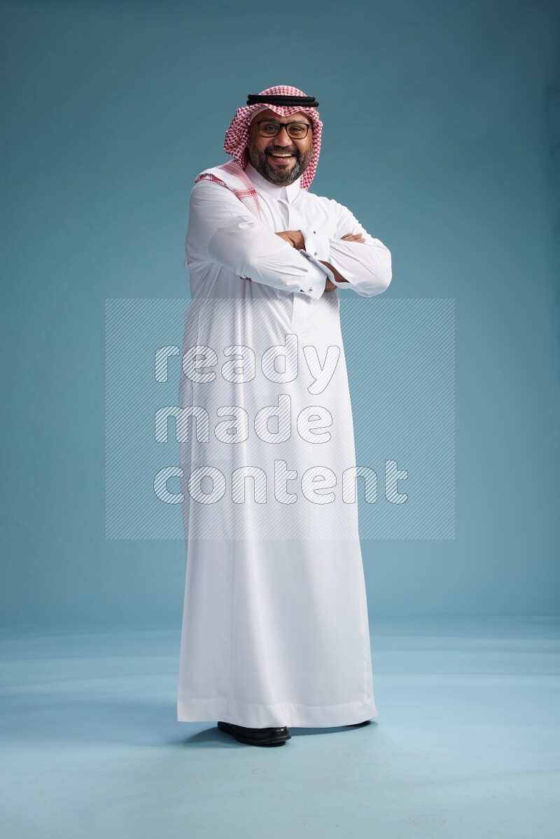 Saudi Man with shimag Standing Interacting with the camera on blue background