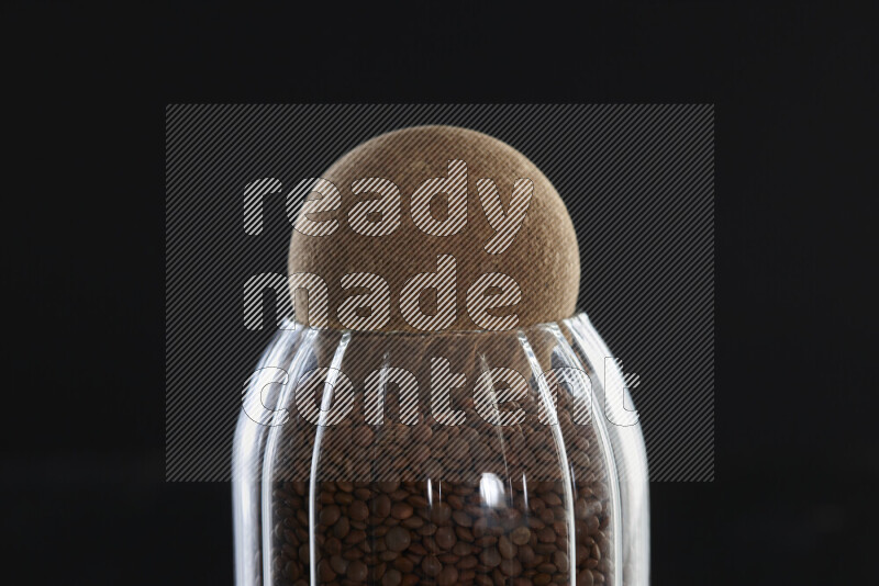 Brown lentils in a glass jar on black background