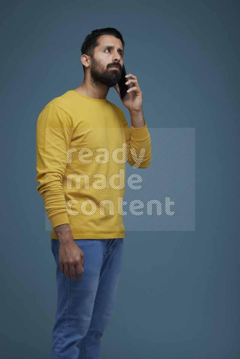 A man having a calling in a blue background wearing a yellow shirt