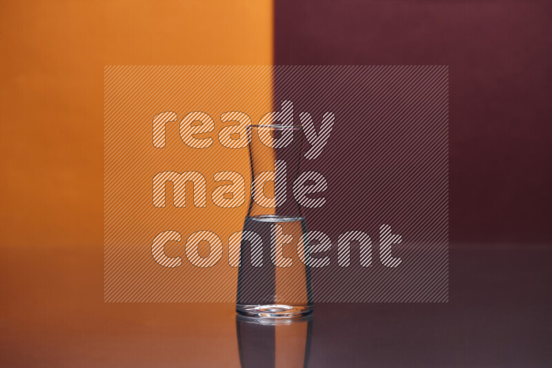 The image features a clear glassware filled with water, set against orange and dark red background