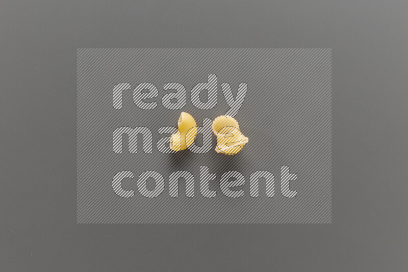 Elbow pasta with other types of pasta on grey background