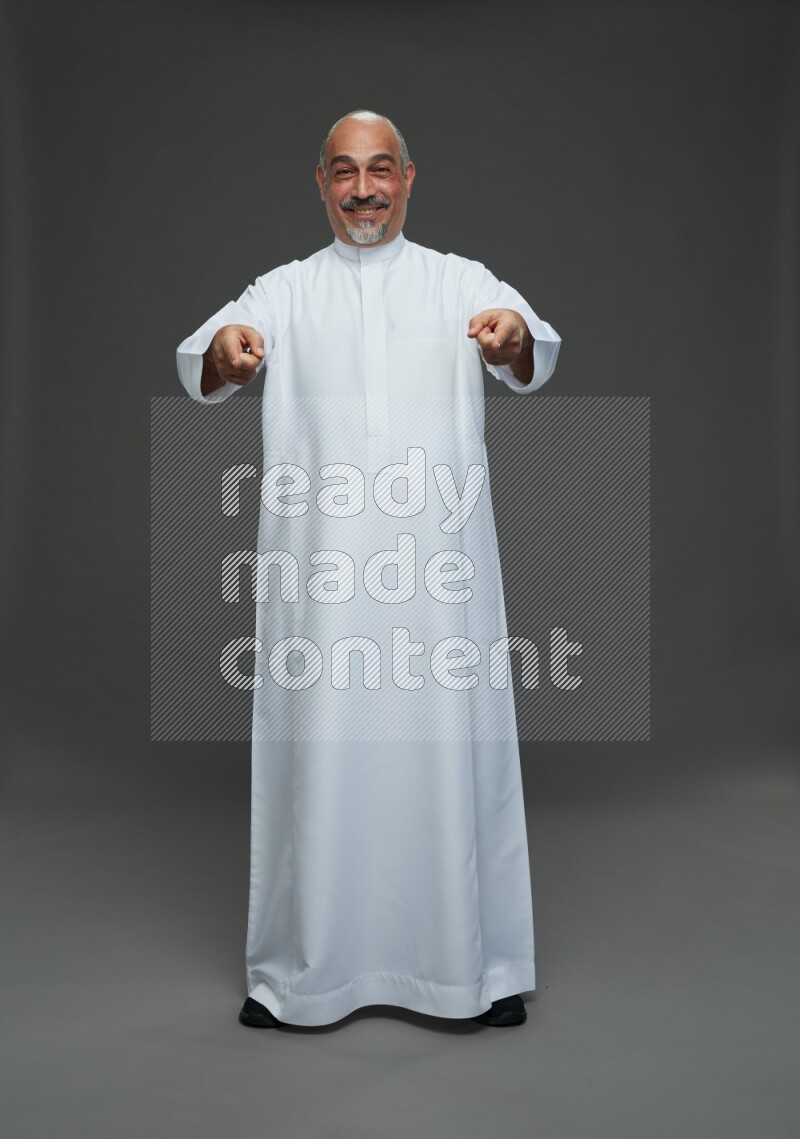 Saudi man without shomag Standing Interacting with the camera on gray background