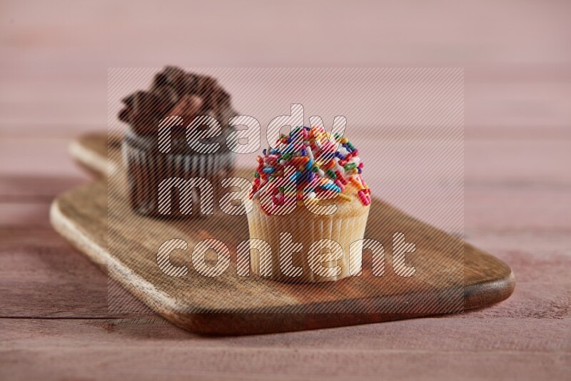 Vanilla mini cupcake topped with sprinkles on a wooden board