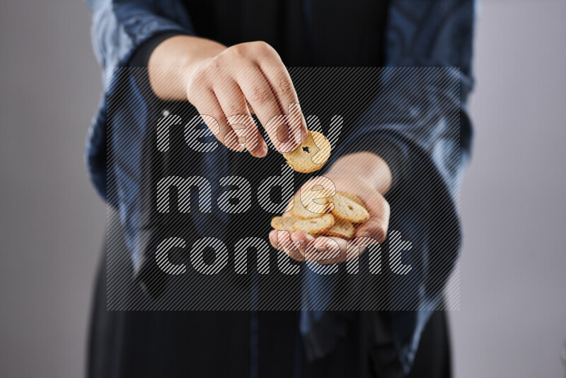 Woman in abaya holding different kinds of snacks in different positions