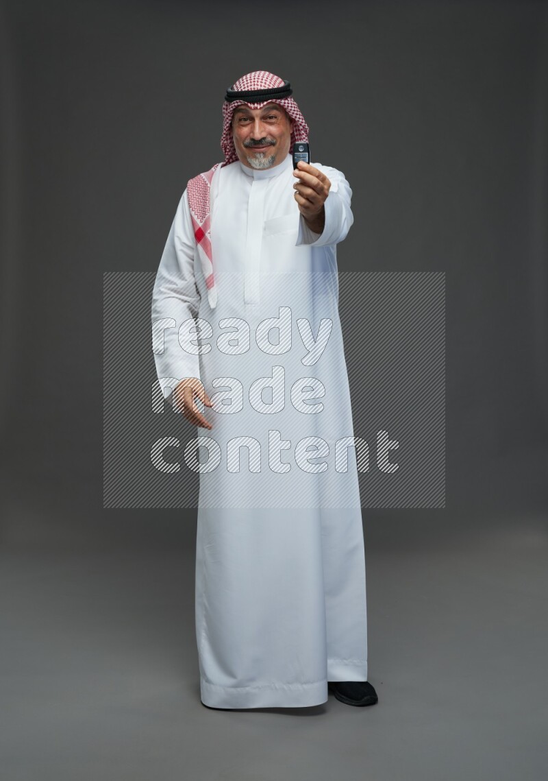 Saudi man with shomag Standing holding car key on gray background