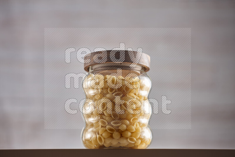 Raw pasta in glass jars on beige background