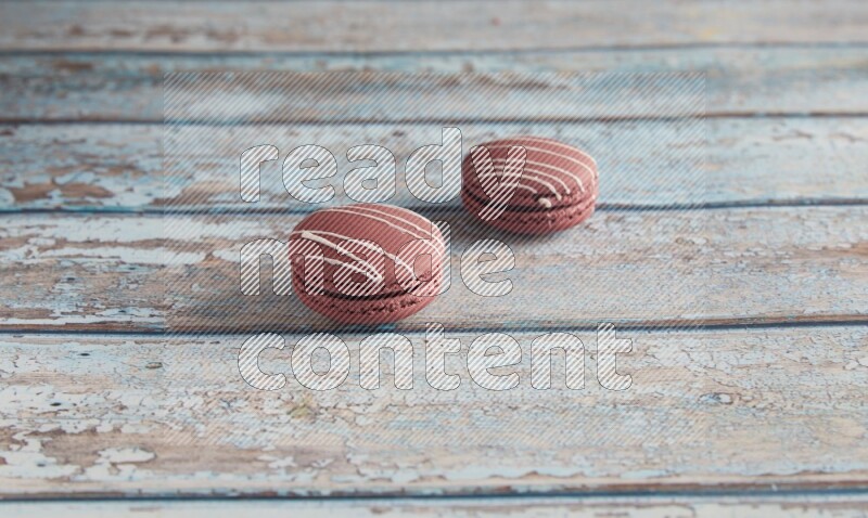 45º Shot of two Red Poppy Flower macarons on light blue wooden background