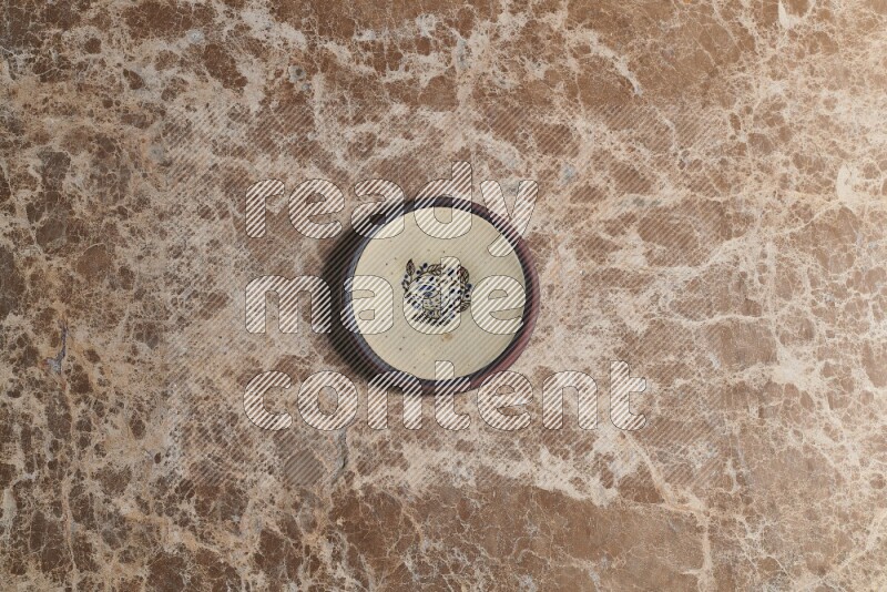 A decorative pottery plate on beige marble background