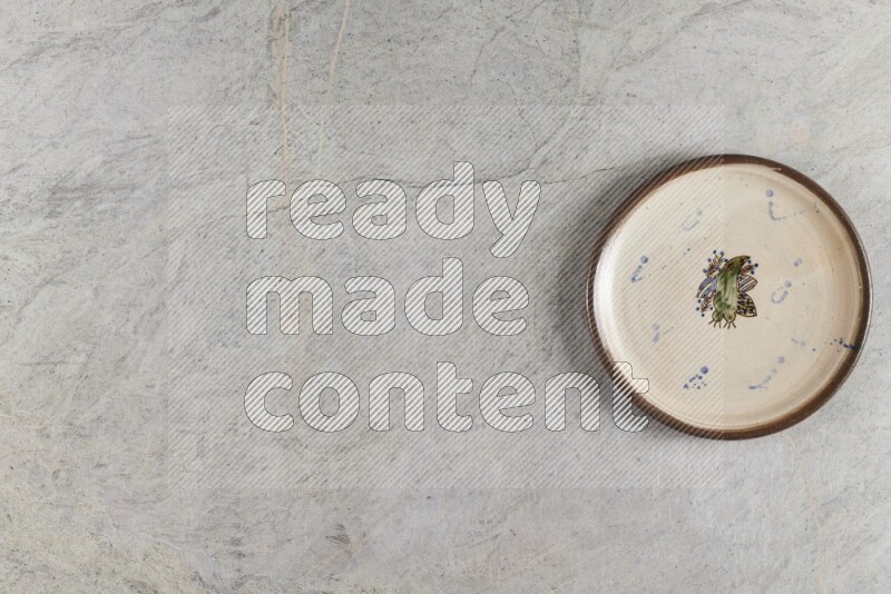 A decorative pottery plate on grey marble background