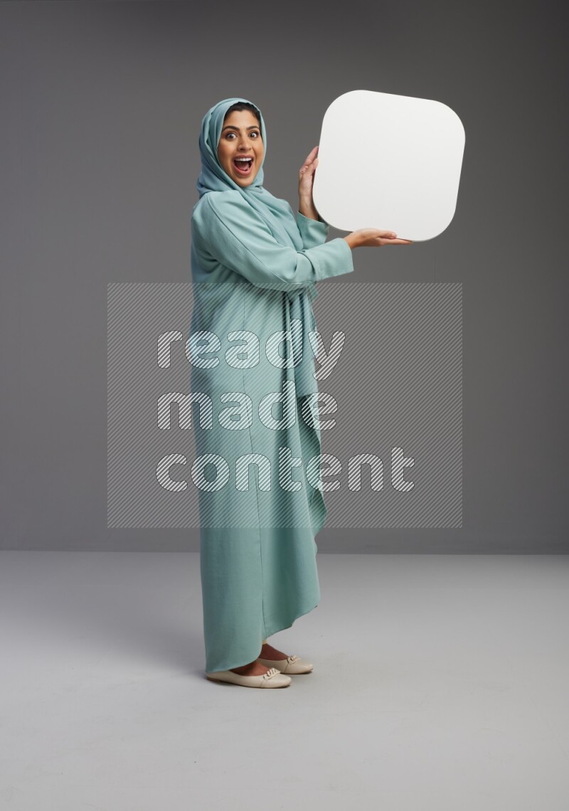 Saudi Woman wearing Abaya standing holding social media sign on Gray background