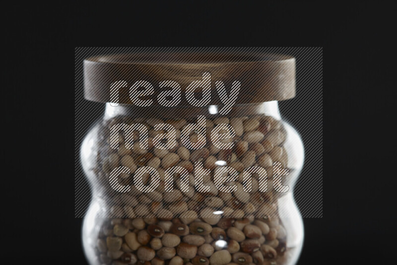Black-eyed peas in a glass jar on black background