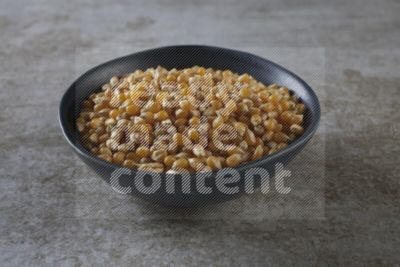 corn kernel in a black ceramic bowl on a grey textured countertop