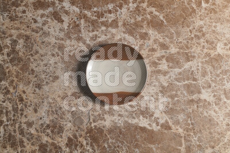 A decorative pottery plate on beige marble background