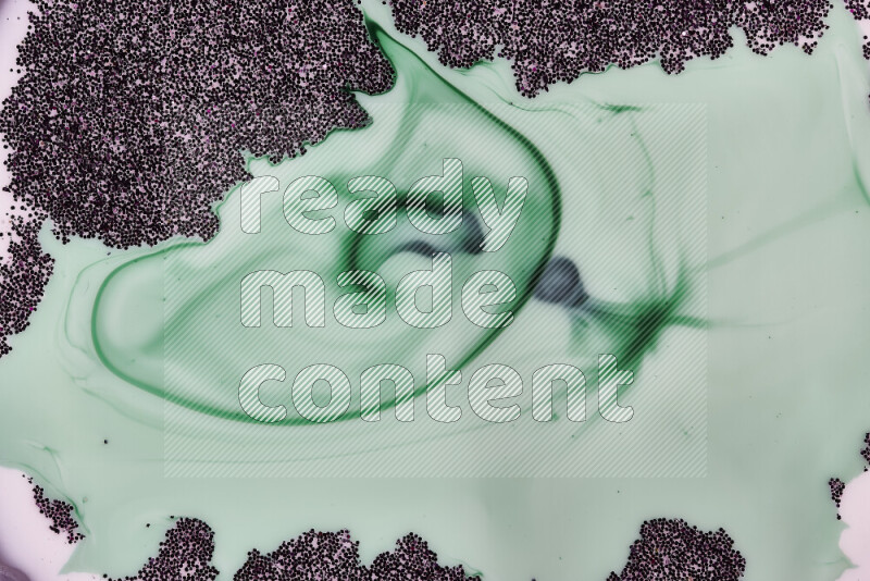 A close-up of sparkling purple glitter scattered on swirling green and white background