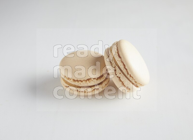 45º Shot of two White Caramel fleur de sel macarons on white background