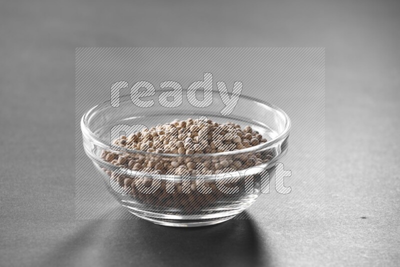 A glass bowl full of white peppers on black flooring
