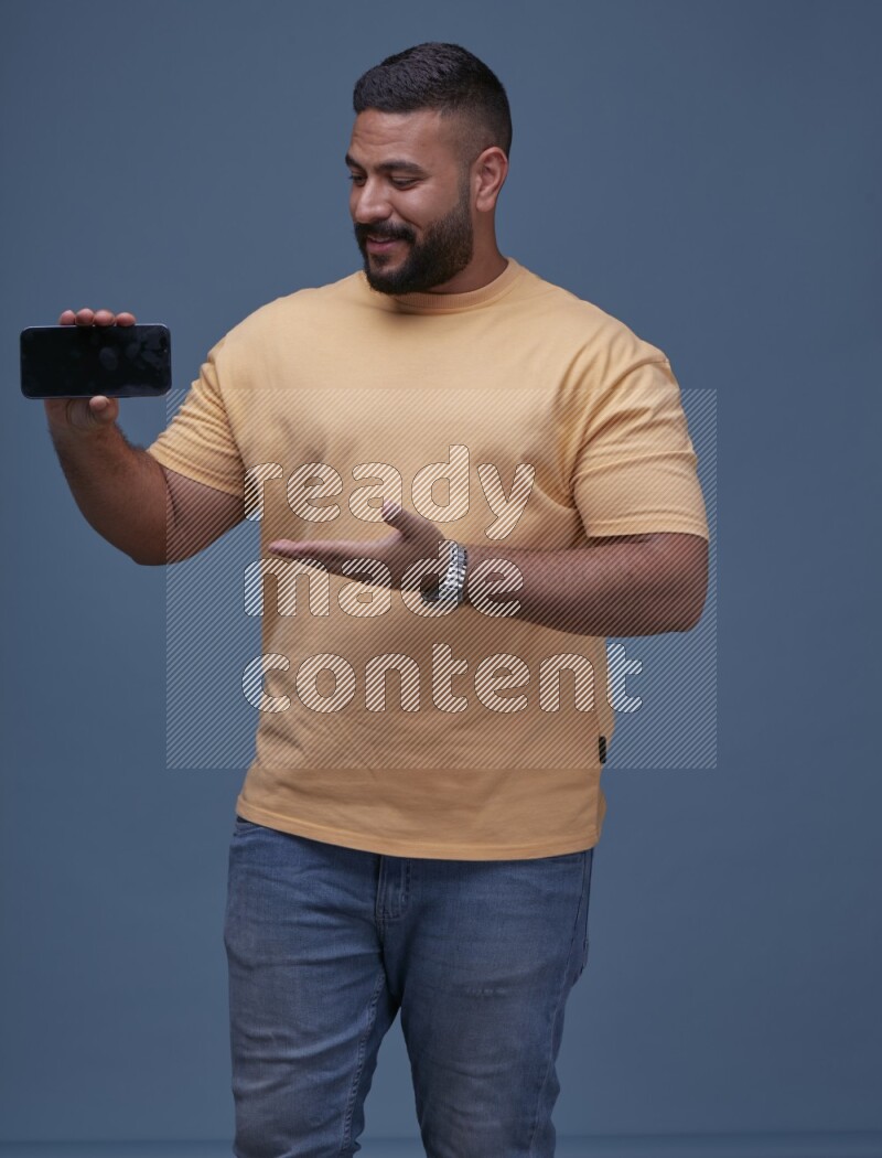 A man Showing His Smart Phone on Blue Background wearing Orange T-shirt