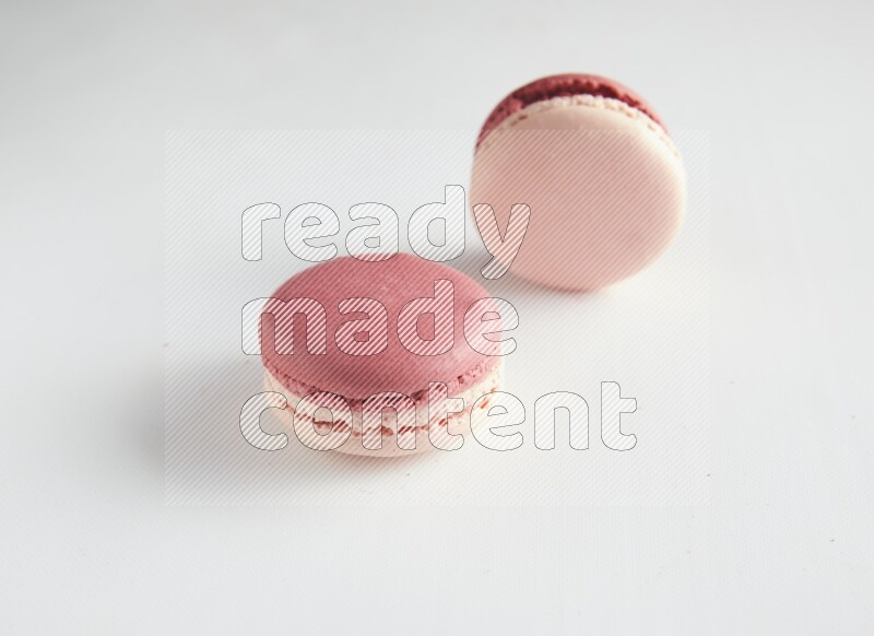 45º Shot of two Pink Litchi Raspberry macarons on white background