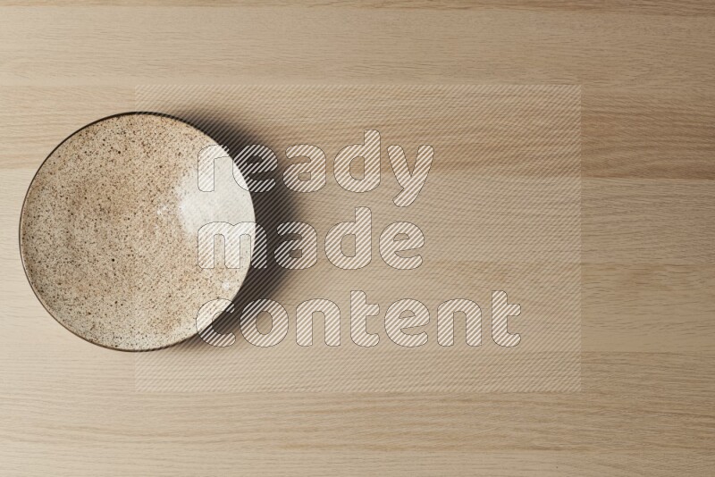 صحن فخاري متعدد الألوان على خلفية خشبية فاتحة