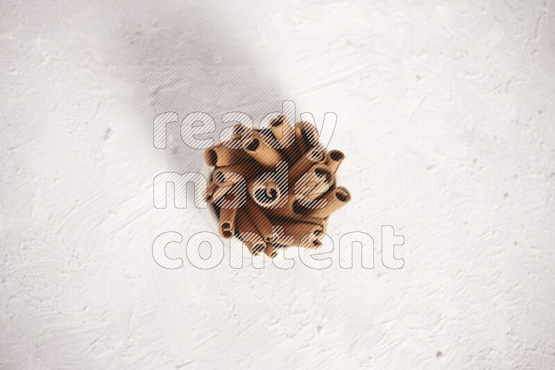 Cinnamon sticks in a beige bowl on a white background