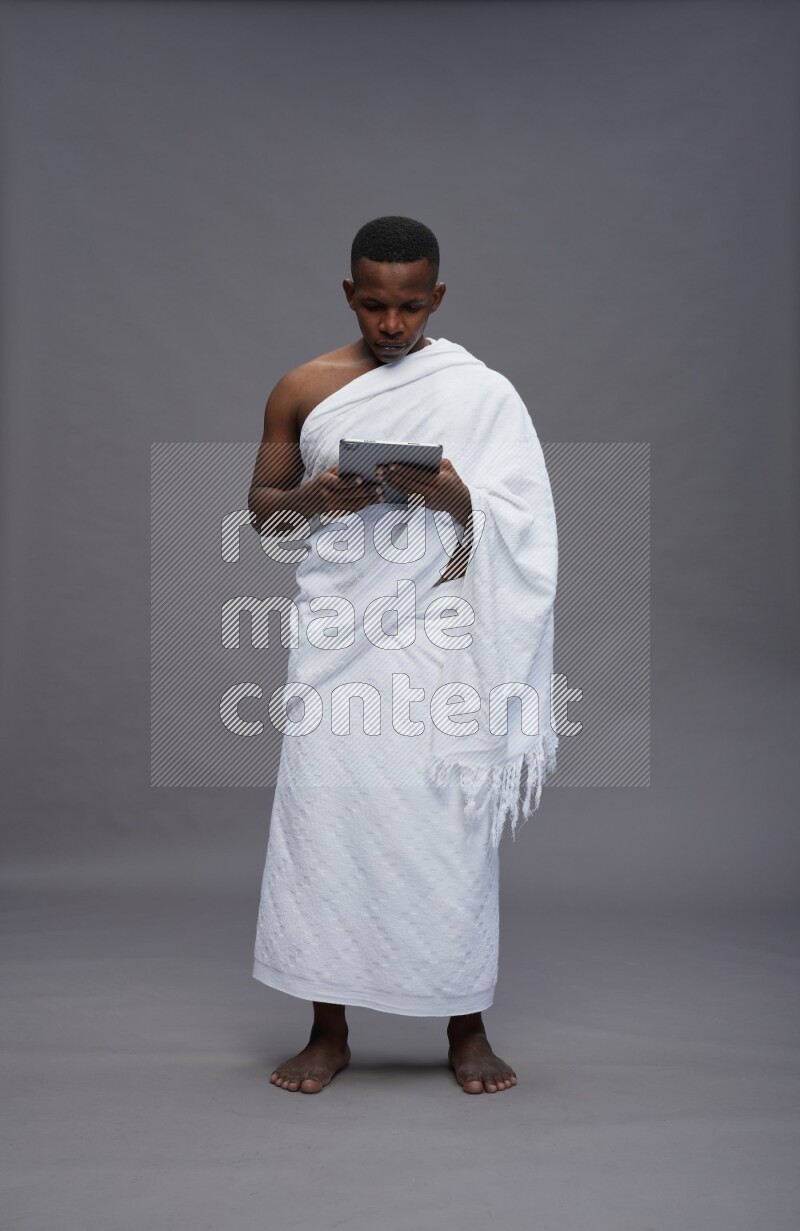 A man wearing Ehram Standing working on tablet on gray background