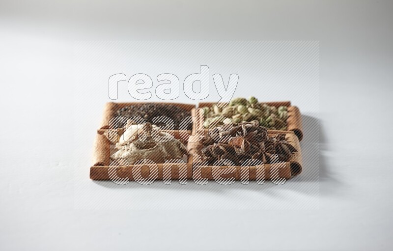 4 squares of cinnamon sticks full of tea, cardamom, star anise and ginger on white flooring